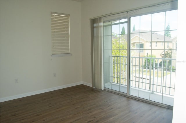 spare room featuring baseboards, wood finished floors, and a wealth of natural light