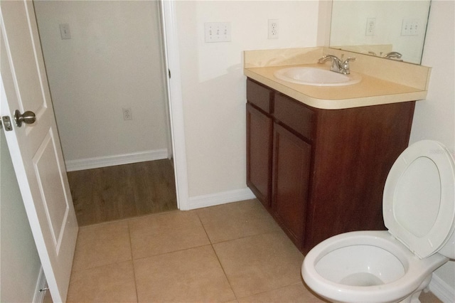 half bath with vanity, tile patterned flooring, baseboards, and toilet