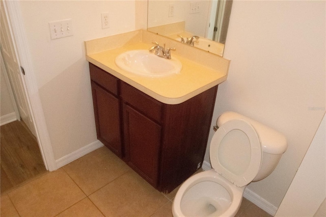 half bathroom with vanity, baseboards, and toilet