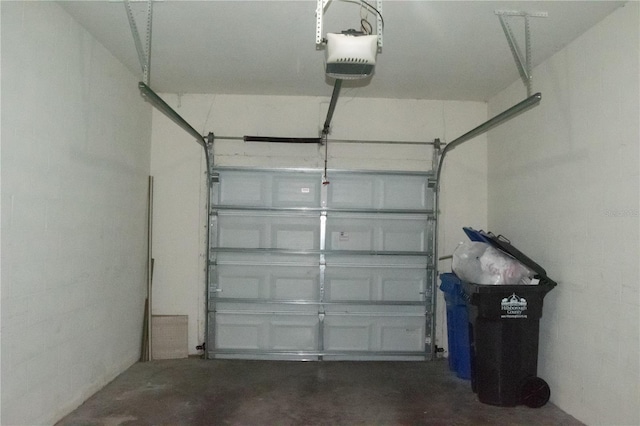 garage with a garage door opener and concrete block wall