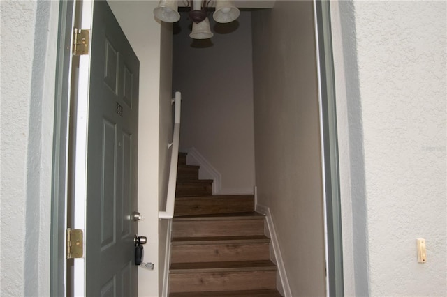 stairway with an inviting chandelier and wood finished floors