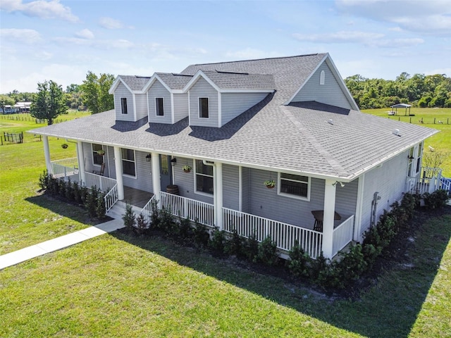 view of front of house featuring covered porch, a shingled roof, and a front yard