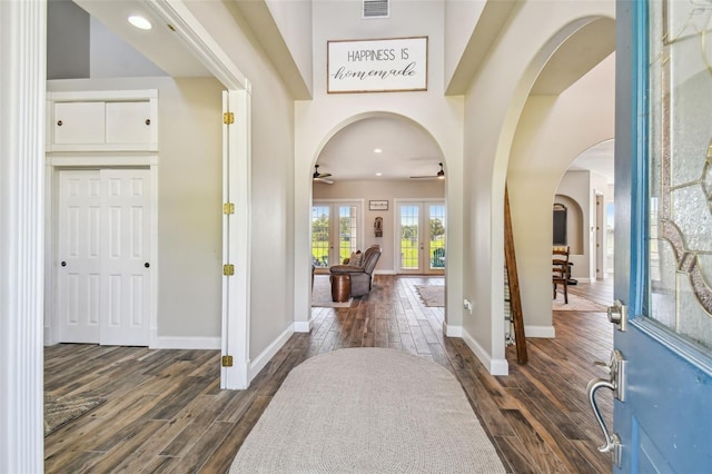 foyer with baseboards, a ceiling fan, dark wood finished floors, and arched walkways