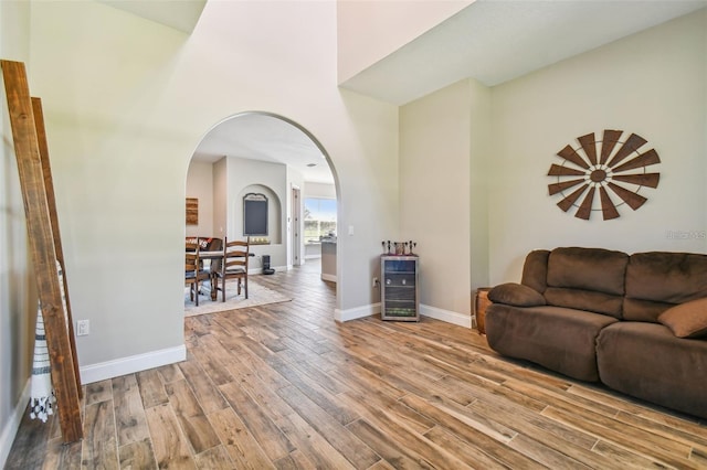 living room with arched walkways, baseboards, wood finished floors, and a high ceiling
