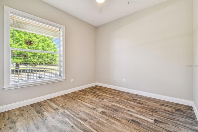 spare room with baseboards, ceiling fan, and wood finished floors