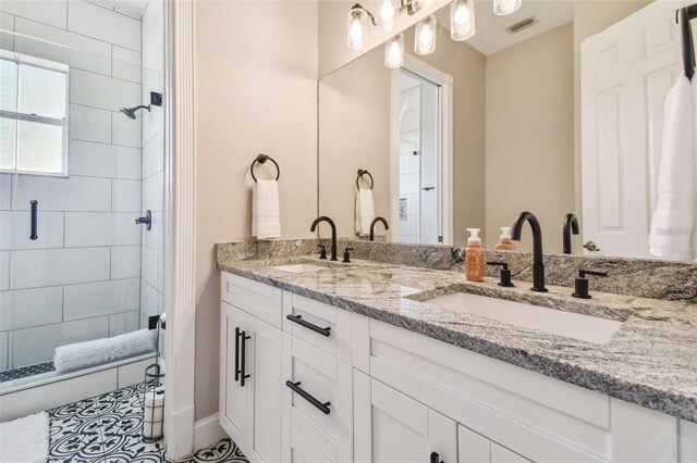 bathroom with visible vents, a sink, double vanity, and tiled shower