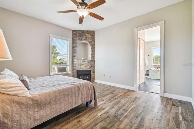 bedroom with baseboards, multiple windows, a brick fireplace, and wood finished floors