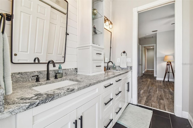 bathroom with baseboards, a sink, and double vanity