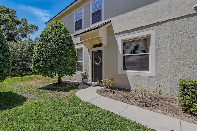 property entrance featuring a lawn and stucco siding