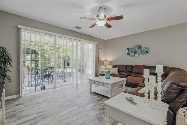 living area with baseboards, ceiling fan, visible vents, and light wood-style flooring