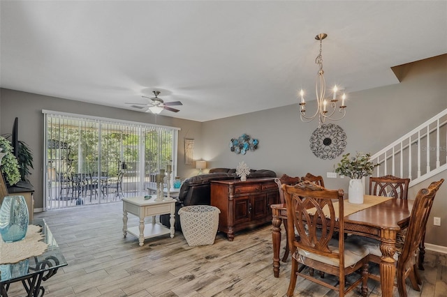 dining room featuring ceiling fan with notable chandelier, stairs, and light wood-style flooring