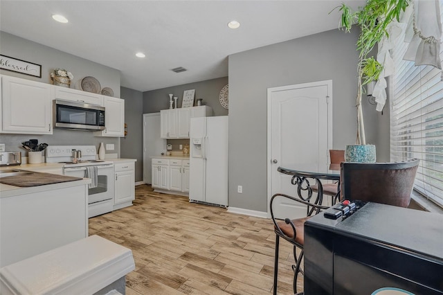 kitchen with light wood-type flooring, white cabinetry, visible vents, and white appliances