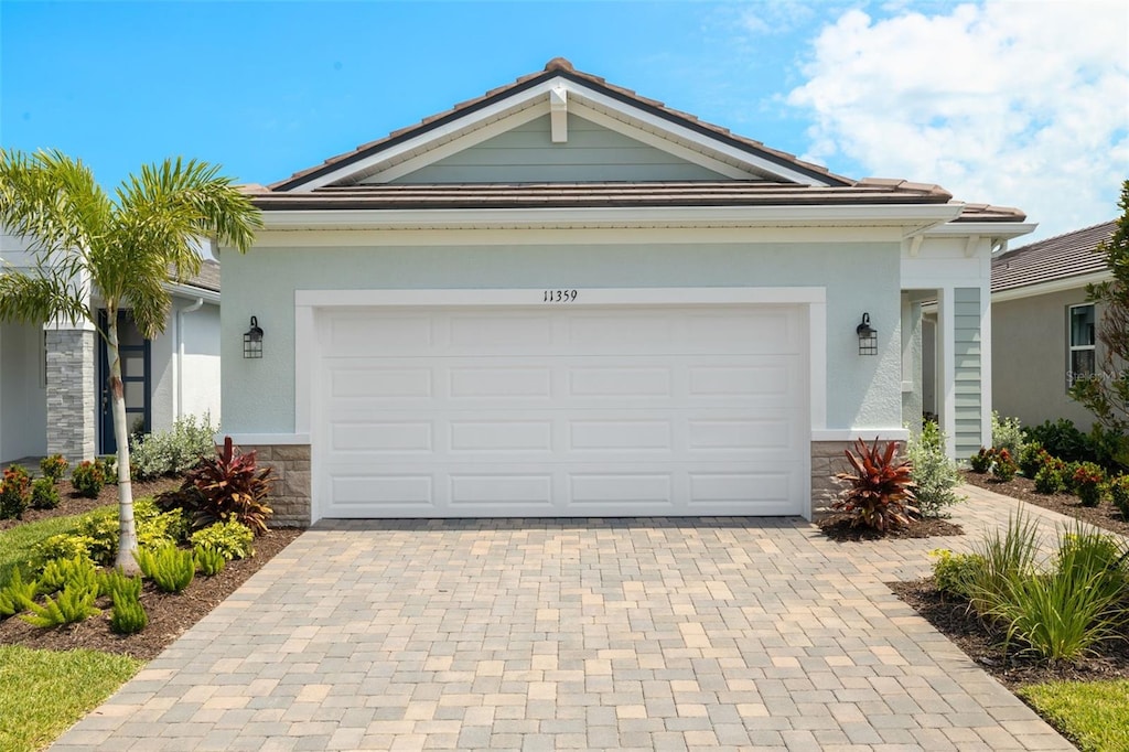 11359 Boundless Ter, Venice, FL 34293 - ranch-style home with decorative driveway, stone siding, a garage, and stucco siding