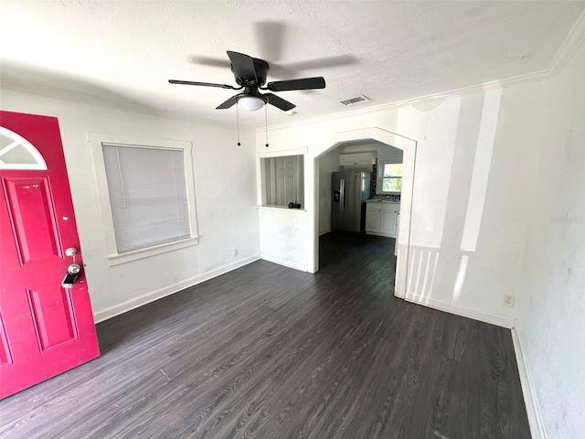 interior space featuring ceiling fan, a textured ceiling, baseboards, dark wood-style floors, and ornamental molding