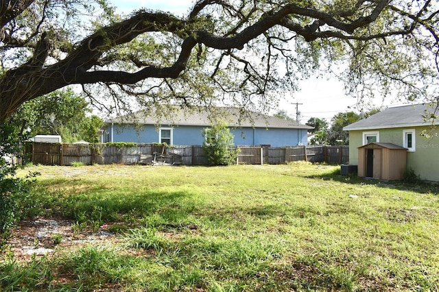 view of yard featuring a storage shed, fence, and an outbuilding