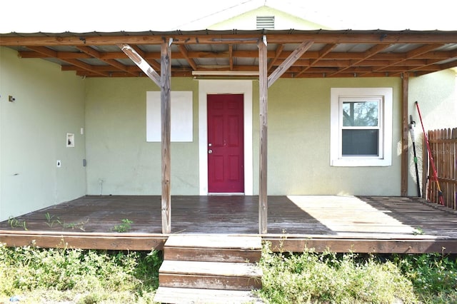 entrance to property featuring a deck and stucco siding
