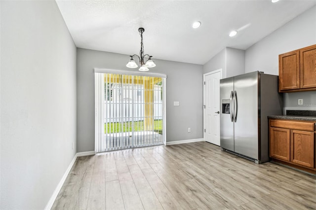 kitchen featuring stainless steel refrigerator with ice dispenser, a chandelier, light wood-style flooring, brown cabinetry, and baseboards