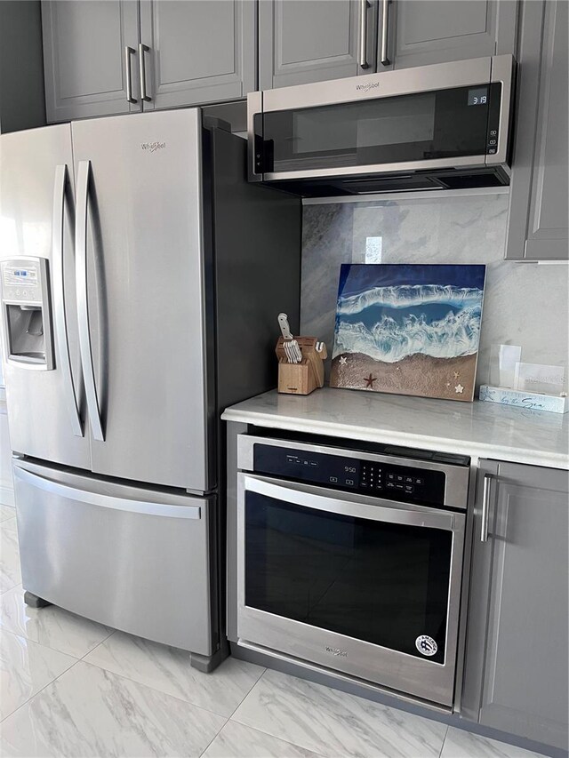 kitchen with gray cabinetry, light countertops, stainless steel appliances, and marble finish floor