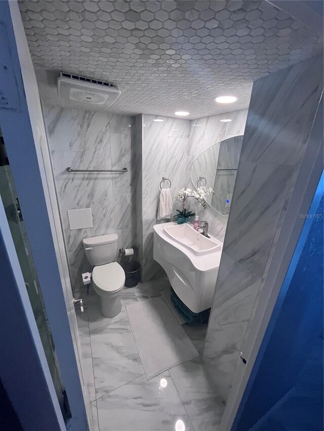 bathroom featuring toilet, tile walls, and marble finish floor