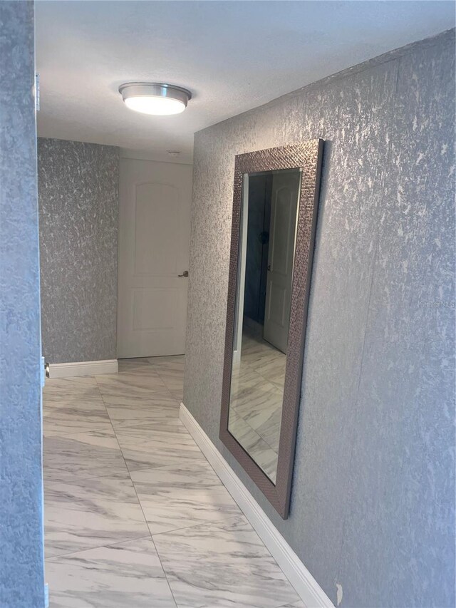 corridor with baseboards and marble finish floor