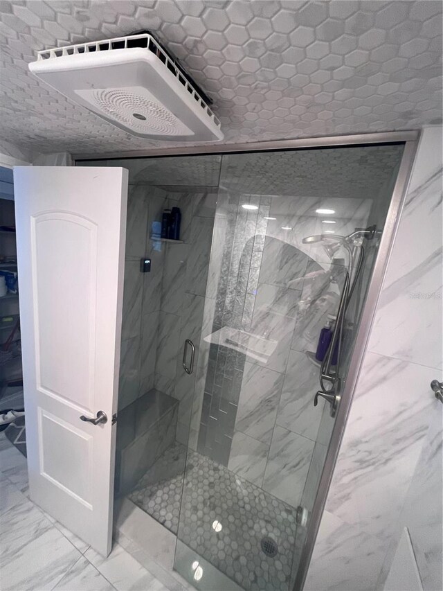 full bath featuring marble finish floor and a stall shower