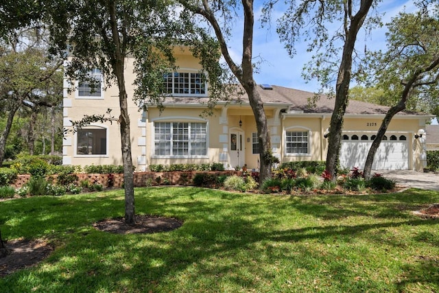 view of front of home featuring a garage, a front lawn, stucco siding, and driveway
