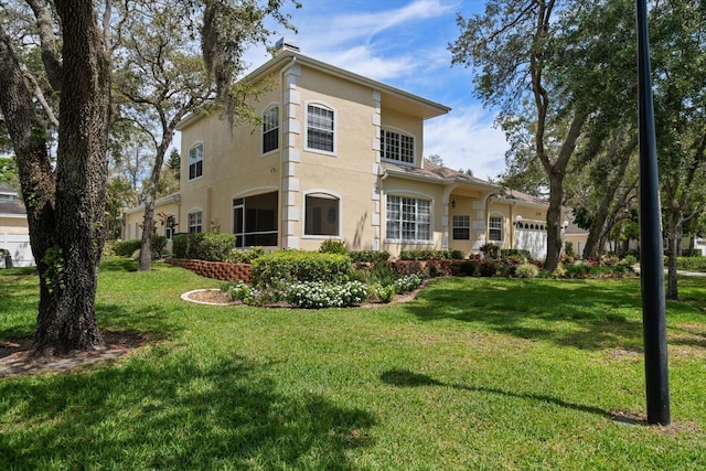 back of property with a lawn, an attached garage, and stucco siding
