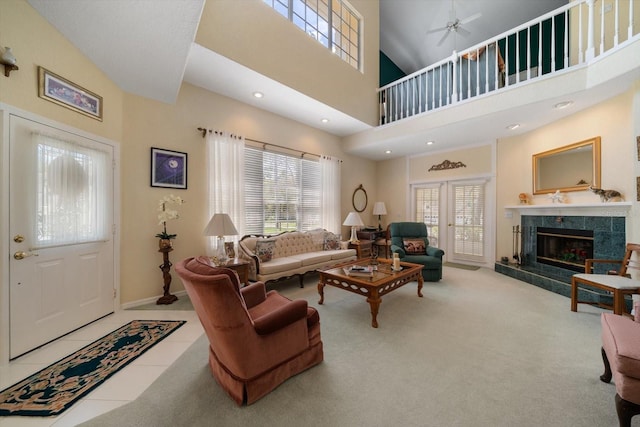 living room featuring a ceiling fan, a towering ceiling, a wealth of natural light, and a fireplace