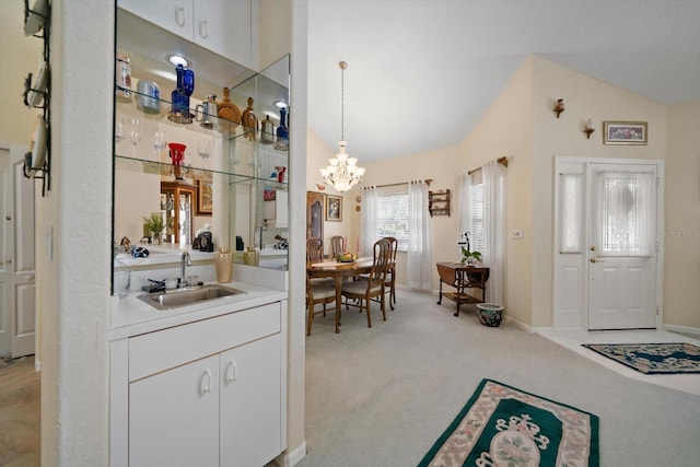 bar featuring a notable chandelier, light carpet, a sink, baseboards, and lofted ceiling