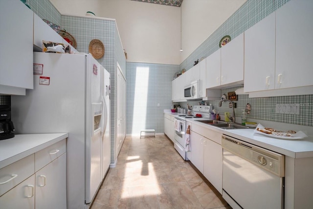 kitchen with white appliances, white cabinets, a sink, and light countertops