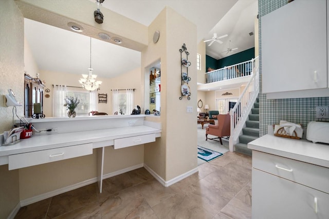 bathroom with baseboards, a high ceiling, and ceiling fan with notable chandelier