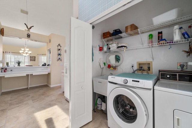 washroom with laundry area, visible vents, washing machine and clothes dryer, a sink, and a notable chandelier