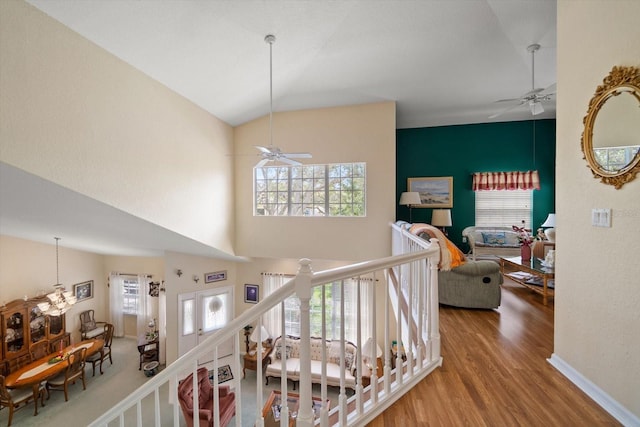 interior space with a high ceiling, ceiling fan with notable chandelier, and wood finished floors