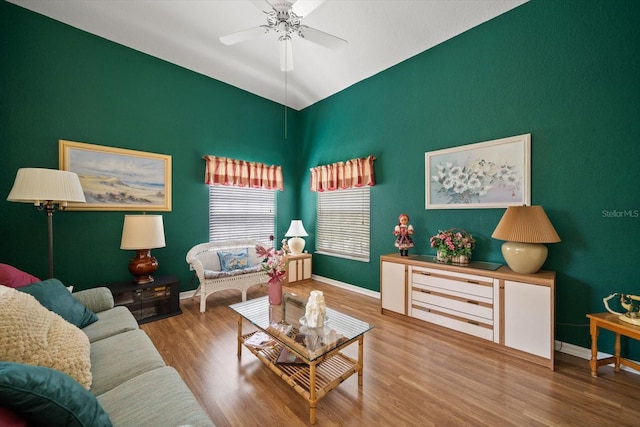 living area featuring vaulted ceiling, baseboards, a ceiling fan, and wood finished floors