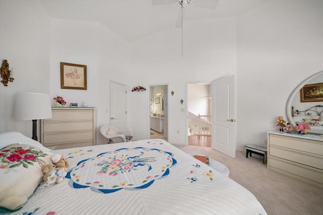 carpeted bedroom with ensuite bathroom, ceiling fan, and high vaulted ceiling