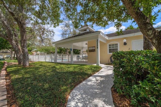 exterior space with a ceiling fan, fence, a front lawn, a patio, and stucco siding