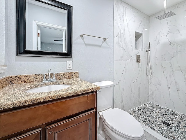 full bath with toilet, a marble finish shower, and vanity
