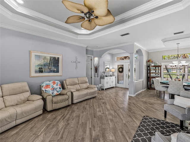 2908 89th Ave E, Parrish, FL 34219 - living room featuring arched walkways, a tray ceiling, wood finished floors, crown molding, and a chandelier