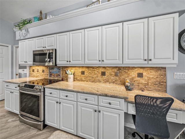 2908 89th Ave E, Parrish, FL 34219 - kitchen featuring stainless steel appliances, white cabinetry, decorative backsplash, and light wood-style flooring