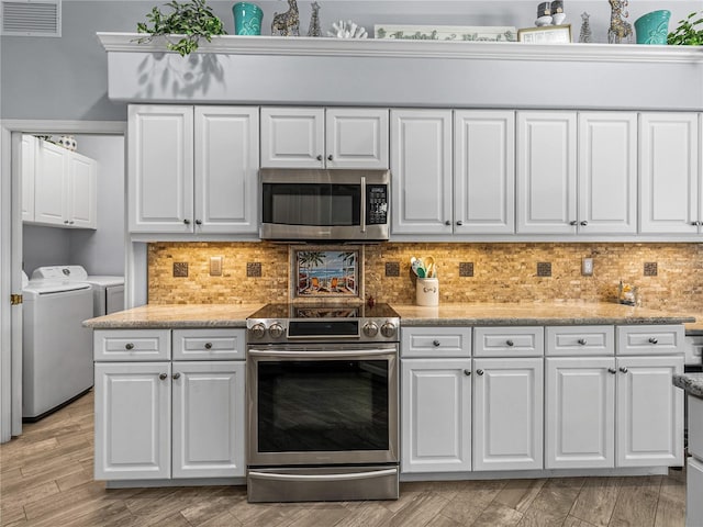 2908 89th Ave E, Parrish, FL 34219 - kitchen featuring appliances with stainless steel finishes, washing machine and clothes dryer, white cabinets, backsplash, and light wood-style floors