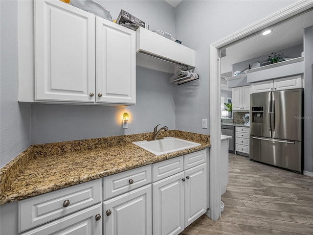 2908 89th Ave E, Parrish, FL 34219 - kitchen with appliances with stainless steel finishes, a sink, white cabinets, wood finished floors, and stone counters