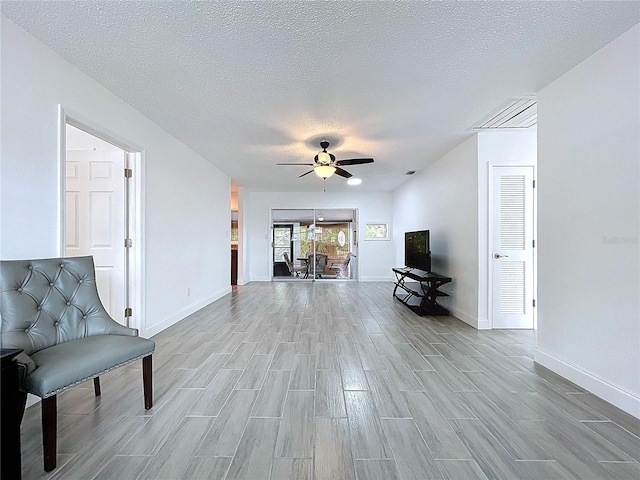 unfurnished room featuring baseboards, a ceiling fan, light wood finished floors, and a textured ceiling