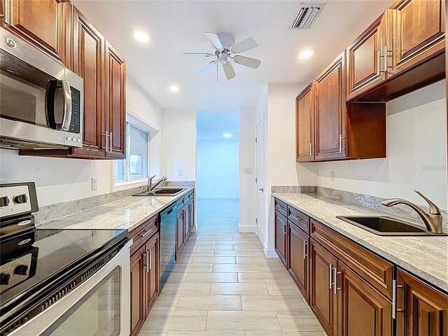 kitchen featuring a sink, a ceiling fan, light stone countertops, and stainless steel appliances