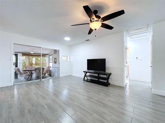 living room with visible vents, baseboards, wood tiled floor, a textured ceiling, and a ceiling fan