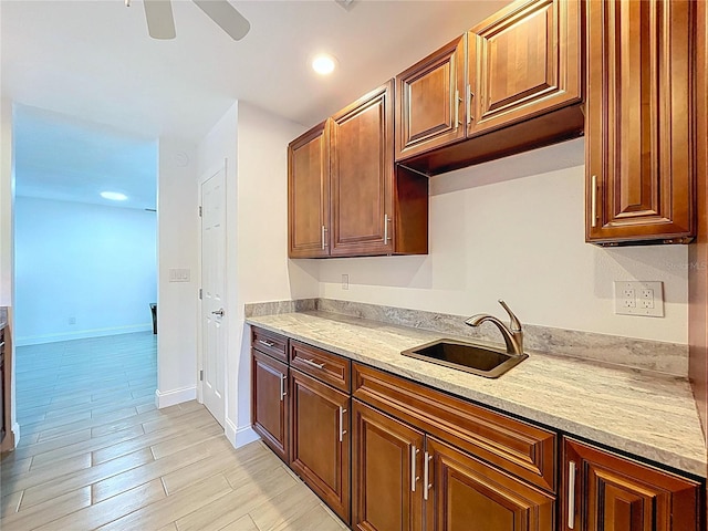 kitchen featuring ceiling fan, a sink, baseboards, light wood-style floors, and recessed lighting