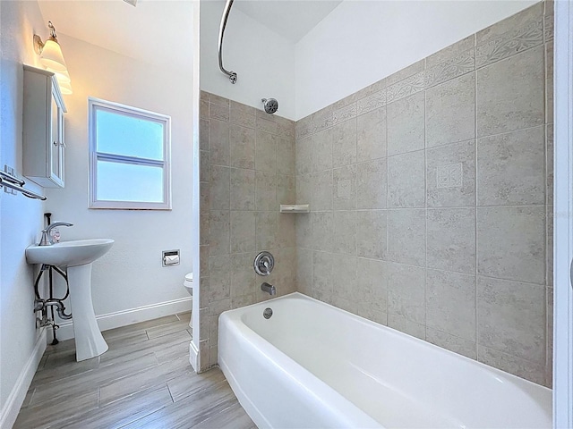 bathroom with shower / bath combination, baseboards, toilet, and wood finished floors
