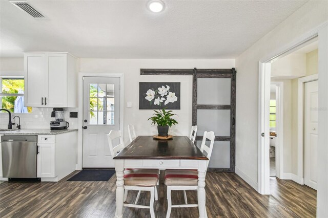 kitchen with stainless steel dishwasher, dark wood-style floors, and plenty of natural light