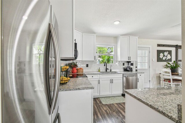 kitchen with dark wood-style flooring, white cabinets, a sink, backsplash, and stainless steel appliances