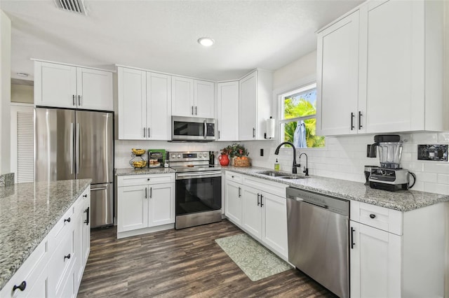 kitchen with backsplash, visible vents, appliances with stainless steel finishes, dark wood finished floors, and a sink