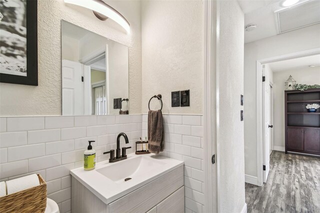 bathroom with a textured wall, vanity, tile walls, wood finished floors, and visible vents